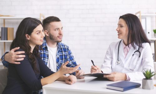 Cheerful doctor talking with millennial family about health care